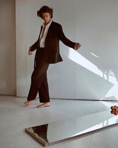 a man in a suit and tie standing on top of an upside down mirrored surface