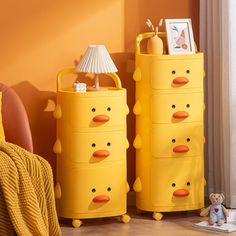 a yellow dresser with two drawers and a teddy bear next to it