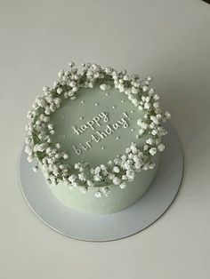 a birthday cake decorated with white flowers and the words happy birthday written in frosting