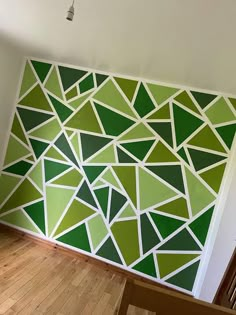 a green and white geometric wallpaper in an empty room with stairs leading up to the second floor