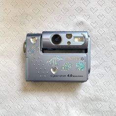 a silver camera sitting on top of a white blanket