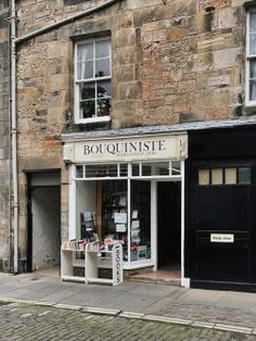 the outside of a book store on a cobblestone street in front of a stone building