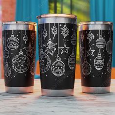 three black and silver cups with christmas ornaments on them