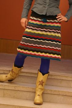 a woman in cowboy boots and a colorful skirt standing on steps with her hands on her hips