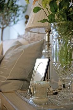 a glass vase filled with flowers sitting on top of a table next to a lamp