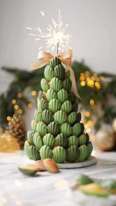 a green christmas tree made out of bananas and nuts with a sparkler in the background