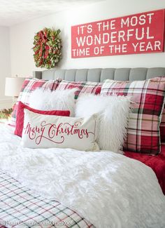 a bedroom decorated for christmas with red and white pillows, plaid bedding and decorations