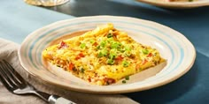 an omelet on a plate with a fork next to it and another dish in the background