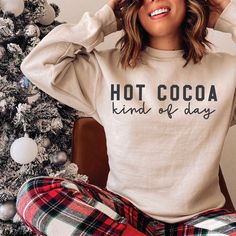 a woman sitting in front of a christmas tree with her hands on her head and wearing pajamas