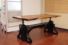 a large wooden table sitting on top of a hard wood floor next to a window