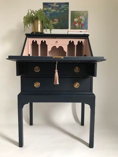 a small black table with drawers on it and a potted plant in the middle