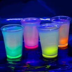 four different colored cups sitting next to each other on a blue surface with the words cool glow cups