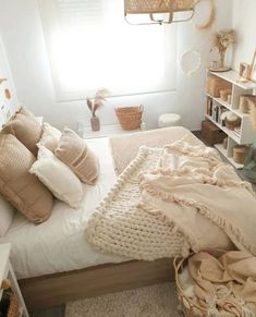 a bed with pillows and blankets on top of it in a bedroom next to a window