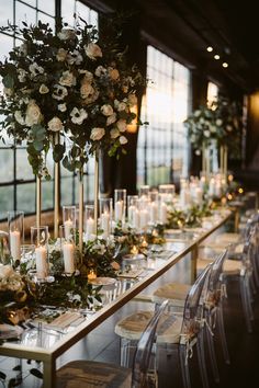 a long table with candles, flowers and greenery is set up for an event