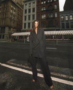 a man is standing in the middle of an empty street with tall buildings behind him