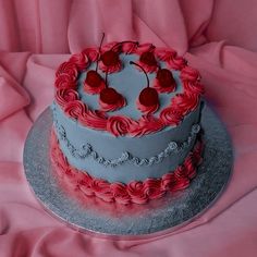 a heart shaped cake with red icing on a silver platter and pink fabric