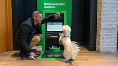 a man is playing with his dog in front of an atm machine