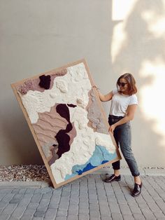 a woman standing next to a large piece of art