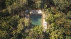 an aerial view of a pool in the middle of some trees, surrounded by water