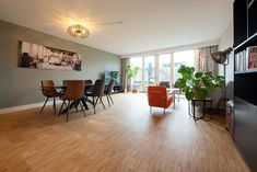 a living room filled with lots of furniture and a large window covered in curtains next to a wooden floor