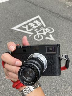 a person holding a camera in their hand on the street with a red wristband