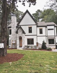 a large white house sitting on top of a lush green field next to a tree