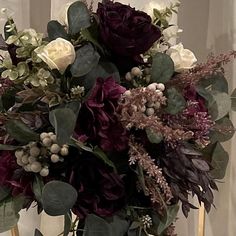 a vase filled with flowers and greenery on top of a table