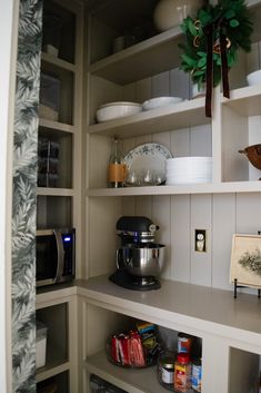 the shelves in this kitchen are filled with dishes and other things to cook for dinner