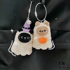 two crocheted items are hanging on a black cloth background, one is wearing a witch hat and the other has a small stuffed animal