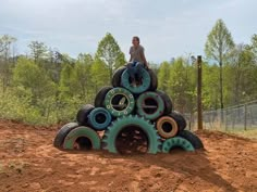 a man standing on top of a pile of tires in the middle of a dirt field