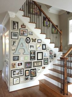 a staircase with many pictures on the wall and framed photos on the wall behind it