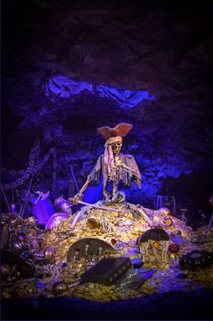 a skeleton is sitting on top of a pile of junk in a cave with other items