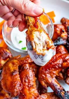 a person dipping sauce on top of chicken wings