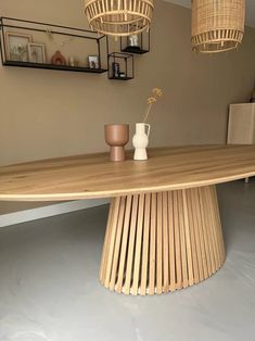 a large wooden table with two vases on it and some hanging lights in the background