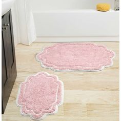 two bathroom rugs on the floor in front of a bathtub