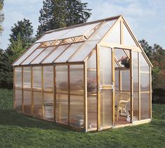 a small greenhouse in the middle of a grassy area with a chair and table inside