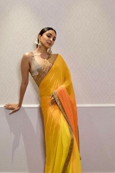 While we were still not over Kiara Advani’s envy-worthy choices for her sister Ishita Advani’s wedding, we happened to deep dive into her style files lately, and boy it was filled to the brim with shimmer, shine & a pinch of sass! The Shershah actress truly knows how to make a mark. Whether it’s trying out neon hues, thigh-high slits, or risque blouses, she has done it all! However, it's her penchant for sarees that has us hooked to bits. Orange Saree, Plain Saree, Yellow Saree, Saree Trends, Kiara Advani, Stylish Sarees, Georgette Saree, Bollywood Girls, Saree Look