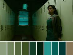 a woman standing in a hallway next to lockers with green and blue colors on them