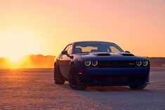 a blue sports car parked in the desert at sunset