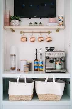 two baskets sit on top of a shelf in front of a tv and coffee maker