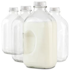 four glass bottles filled with milk on a white background