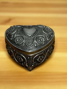 a heart shaped metal box sitting on top of a wooden table