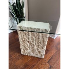 a glass table with a plant in it on top of a hard wood floor next to a window