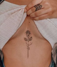 a woman's stomach with a rose tattoo on her left side ribcage