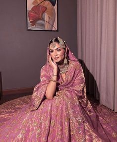 a woman in a pink bridal gown sitting on a bed talking on her cell phone