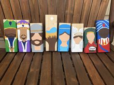 six wooden paintings of different people are on a wood slatted bench, each painted in different colors and sizes