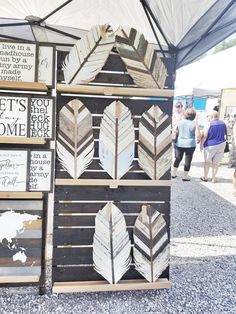 several wooden signs are stacked on top of each other in front of a white tent