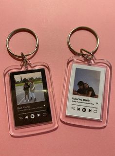 two keychains with pictures attached to them on a pink surface and one has an mp3 player in it