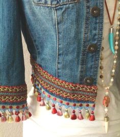 a woman wearing a jean jacket with beads and tassels