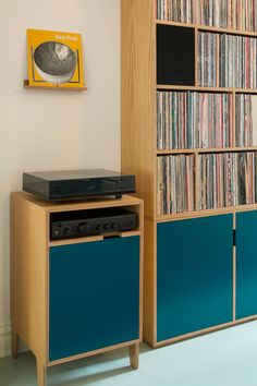 a record player sitting on top of a blue cabinet in front of a bookcase